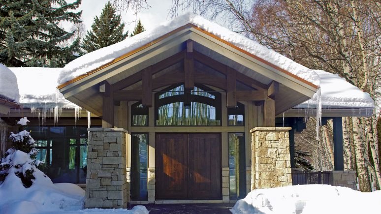 snow covered front of home with Regent Buff rubble natural stone thin veneer installed on exterior walls